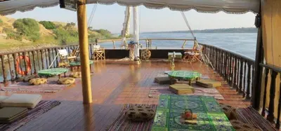 a boat deck with tables and chairs on the water at ايجبت تورز in Luxor