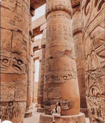 a woman sitting on a pillar in an ancient building at Elbess For Tourism in Jazīrat al ‘Awwāmīyah