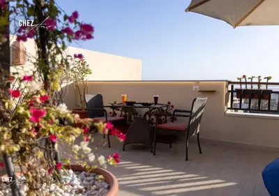 a patio with a table and chairs and flowers at Luxury Rooftop Penthouse Sea View & Pools in Hurghada