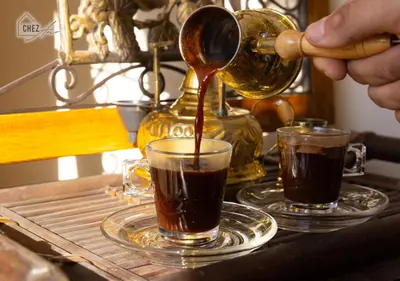 a person pouring coffee into two cups on a table at Mangroovy Retreat Smart home in Hurghada
