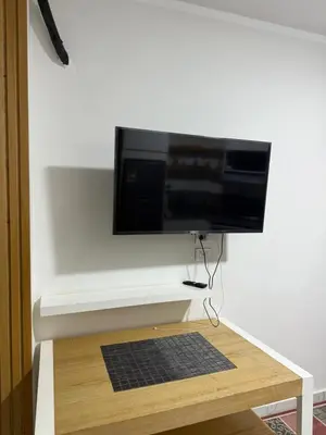 a flat screen tv on a white wall with a black rug at جوليانا الغردقة juliana beach D410 in Hurghada