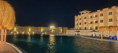 a pool of water in front of a building at night at Bay View Resort Sahl Hashesh in Hurghada