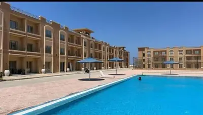 a large pool in front of a building with umbrellas at Bay view in Hurghada