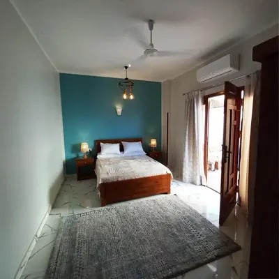 a bedroom with a bed and a blue wall at Christine Home in Luxor