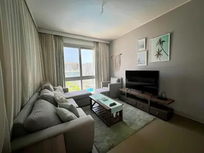 a living room with a couch and a television at Sholan Gouna | Modern 2BR with Pool Access in Hurghada