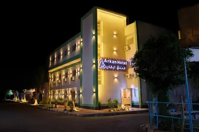 a building with a sign on the side of it at night at Arkan Hotel Qena in Qena