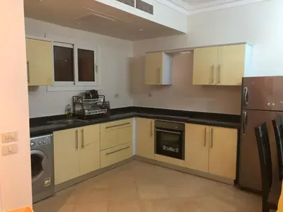 a kitchen with wooden cabinets and a washer and dryer at Sunset Sahl Hashesh in Hurghada