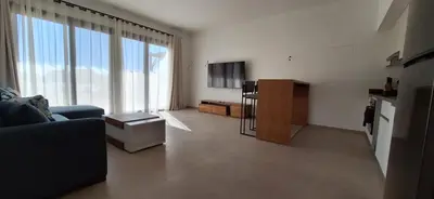 a living room with a blue couch and a tv at El Gouna Paradise Escape 2-Bedroom Ground Floor in El Gouna