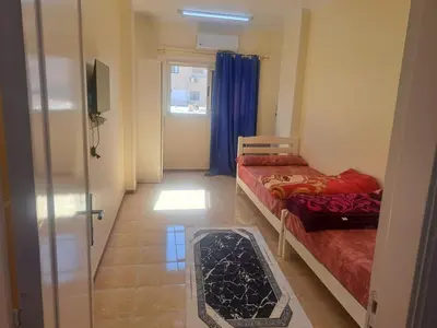 a small room with two beds and a window at Sweet Home 8 in Hurghada