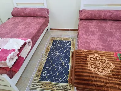 a room with two beds and a rug on the floor at Sweet Home 7 in Hurghada