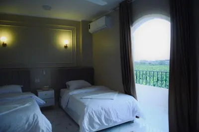 a bedroom with two beds and a window with a balcony at Paradise House Holiday in Luxor