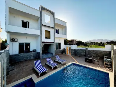 a house with a swimming pool and two chairs at Nefertarie Villa in Luxor