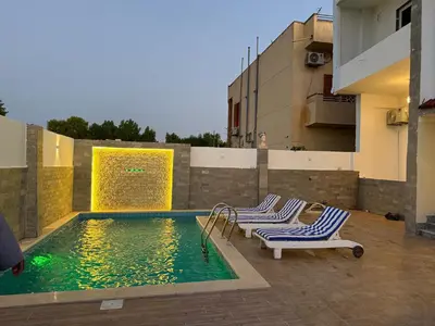 a swimming pool with two lounge chairs next to a building at Nefertarie Villa in Luxor