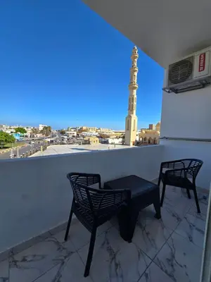two chairs and a table on a balcony with a lighthouse at الغردقة in Hurghada