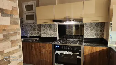 a kitchen with a black stove and wooden cabinets at Aldora residence شقه 3 غرف نوم و2 حمام in Hurghada