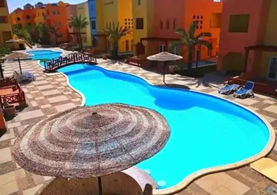 a large swimming pool with an umbrella in a resort at Aldora residence شقه 3 غرف نوم و2 حمام in Hurghada