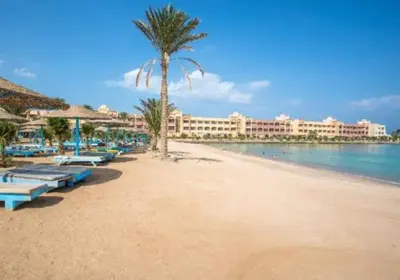 a beach with a palm tree and a hotel at Private Beach Chalet in Orabia in Hurghada