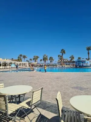 a patio with tables and chairs next to a swimming pool at Veronia gad chalet Mirage bay aqua park in Hurghada