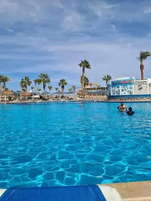a large swimming pool with palm trees in the background at Veronia gad chalet Mirage bay aqua park in Hurghada