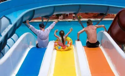 three people on a water slide in a pool at Veronia gad chalet Mirage bay aqua park in Hurghada