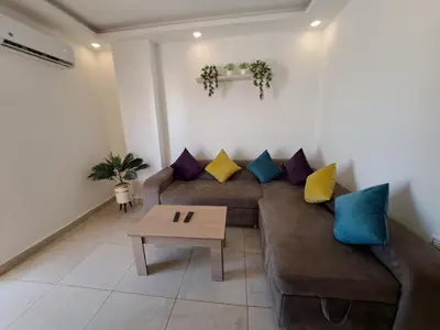 a living room with a brown couch with colorful pillows at Veronia gad chalet Mirage bay aqua park in Hurghada