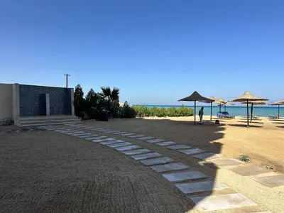 a path on a beach with umbrellas and the ocean at La-Quinta Resort Erika in Hurghada