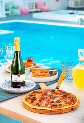 a bottle of wine and a pizza on a table by a pool at One bedroom and reception in Hurghada
