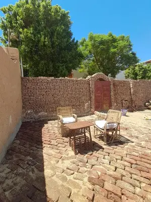 a patio with chairs and a table and a brick wall at Mountain guest house in Luxor