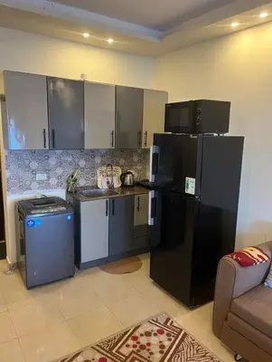 a kitchen with black and white appliances and a couch at Casablanca star hurghada in Hurghada