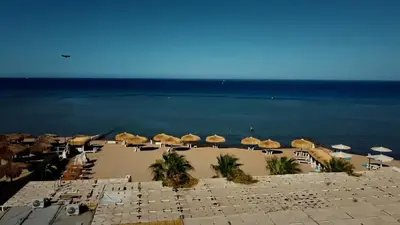 a beach with umbrellas and chairs and the ocean at One bedroom and reception Selena bay, Hurghada in Hurghada