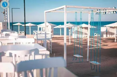 a patio with white tables and chairs and the ocean at Selena Bay in Hurghada