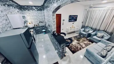 a living room with a tv and a stone wall at Al Mansi Luxury Retreat in Jazīrat al ‘Awwāmīyah