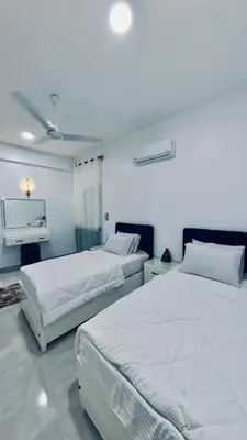 a bedroom with two beds and a tv in it at Al Mansi Luxury Retreat in Jazīrat al ‘Awwāmīyah