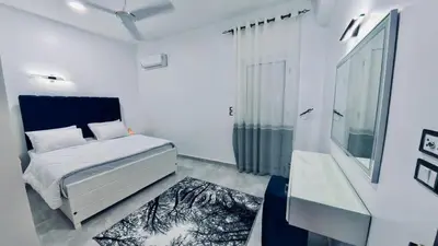a white bedroom with a bed and a window at Al Mansi Luxury Retreat in Jazīrat al ‘Awwāmīyah