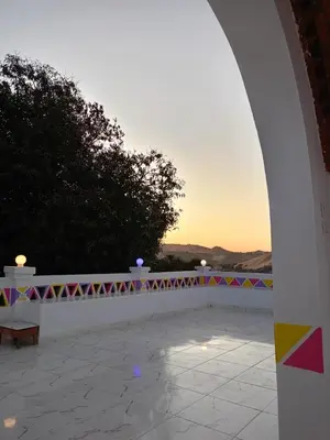 an arch with a bench and a sunset in the background at Reagan House in Aswan