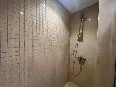a bathroom with a shower with white tiles at Beachside Mangroovy 1BR in Hurghada