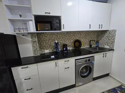 a kitchen with a washing machine and a microwave at Golden Tiba in Hurghada
