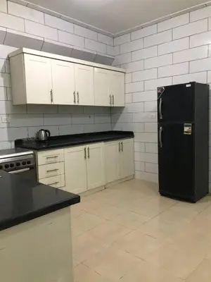 a kitchen with a black refrigerator and white cabinets at Ozera villa - west bank in Luxor