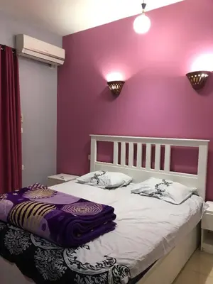 a bedroom with a purple wall and a bed at Ozera villa - west bank in Luxor
