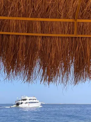 a boat in the water under a straw roof at طيبة جولد Tiba Gold in Hurghada