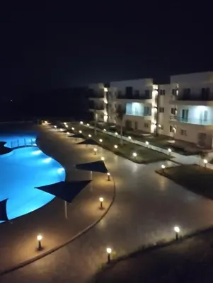 a swimming pool at night with lights and buildings at Panorama View Sahl Hashesh Luxury Suite in Hurghada