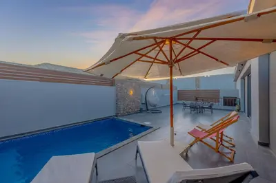 a patio with an umbrella and a swimming pool at Lovely 2BR with Private Pool in Bali El Gouna in Hurghada