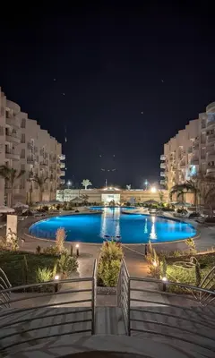 a large pool with blue water at night at Princess Resort hurghada in Hurghada
