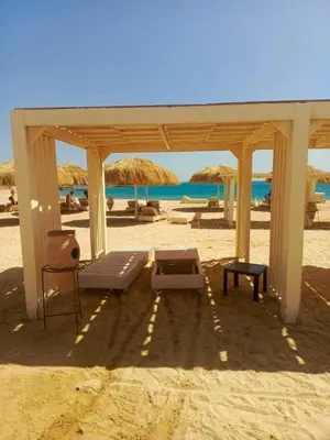 a beach with chairs and umbrellas on the sand at Princess Resort hurghada in Hurghada
