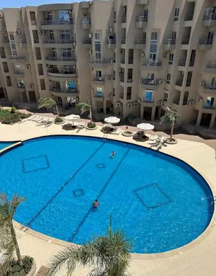 a large swimming pool in front of a large apartment building at Princess Resort hurghada in Hurghada
