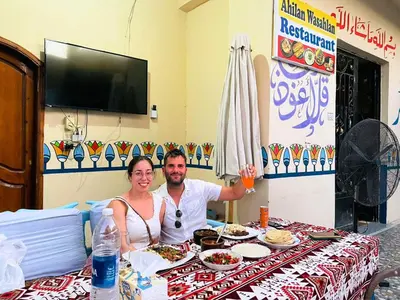 a man and a woman sitting at a table with food at Luxor Hotel in Luxor
