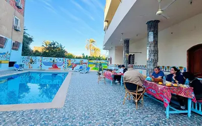 a group of people sitting at tables next to a pool at Luxor Hotel in Luxor