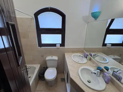 a bathroom with two sinks and a toilet and a mirror at El Gouna Nubian Lagoonfront Villa - 4BR, 9 Guests in El Gouna