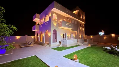 a large house with a courtyard at night at Magic Garden House in Luxor