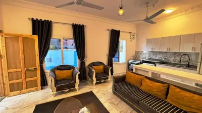 a living room with a couch and chairs and a kitchen at Villa Hofni in Luxor